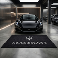 Maserati garage floor mat, 5x7 ft (60x87"), white Maserati Trident crest and wordmark on black background with dimensions shown.
