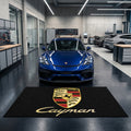 Porsche Cayman garage floor mat, 5x7 ft (60x87"), full Porsche crest shield and gold Cayman script on black background with dimensions shown.
