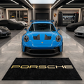Porsche wordmark garage floor mat, 5x7 ft (60x87"), bold gold PORSCHE lettering on black background with dimensions shown.
